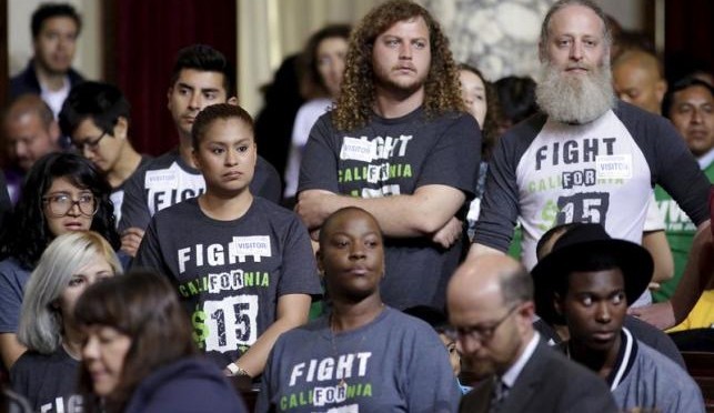 People stand as the Los Angeles City Council prepares to vote on a proposal to raise the minimum wage to $15.00 per hour in Los Angeles, California